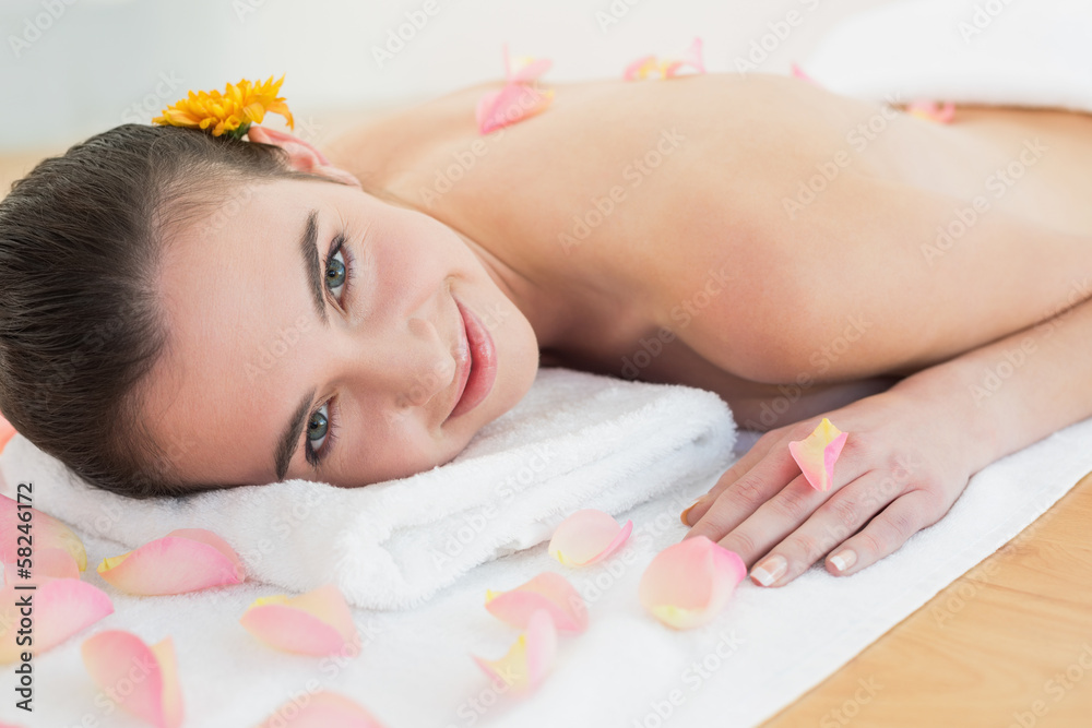 Beautiful woman resting on towel with petals at beauty spa Beautiful woman resting on towel with petals at beauty spa