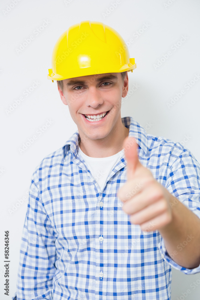 Smiling handyman in yellow hard hat gesturing thumbs up Smiling handyman in yellow hard hat gesturing thumbs up