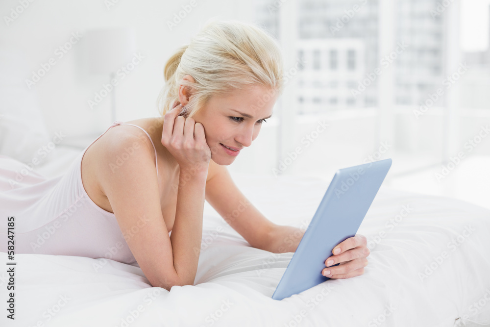 Content casual young blond using tablet PC in bed Content casual young blond using tablet PC in bed