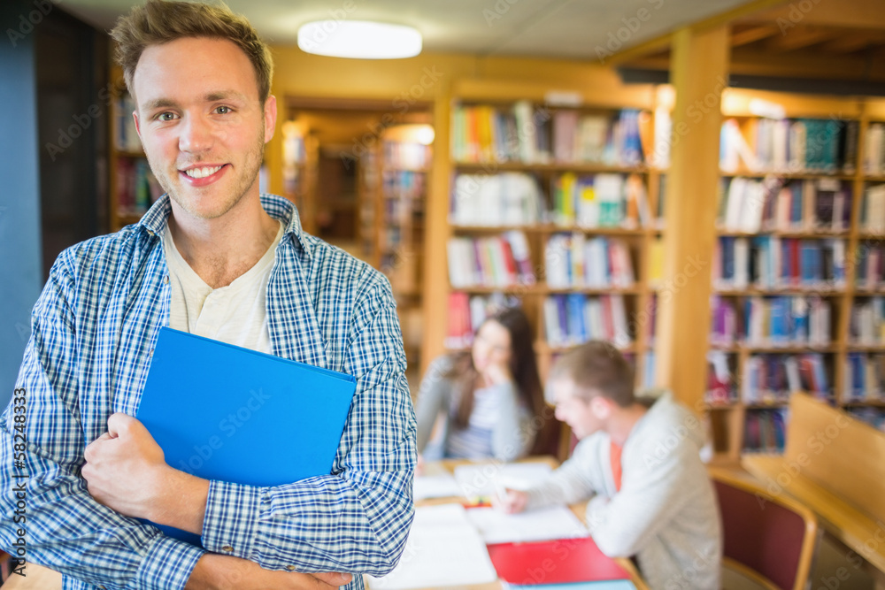 Male student with others in background at library