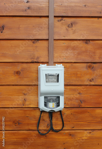 Electricity supply meter on wooden wall front view
