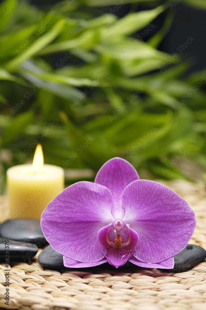 orchid and stones with candle, green leaf on wicker mat orchid and stones with candle, green leaf on wicker mat