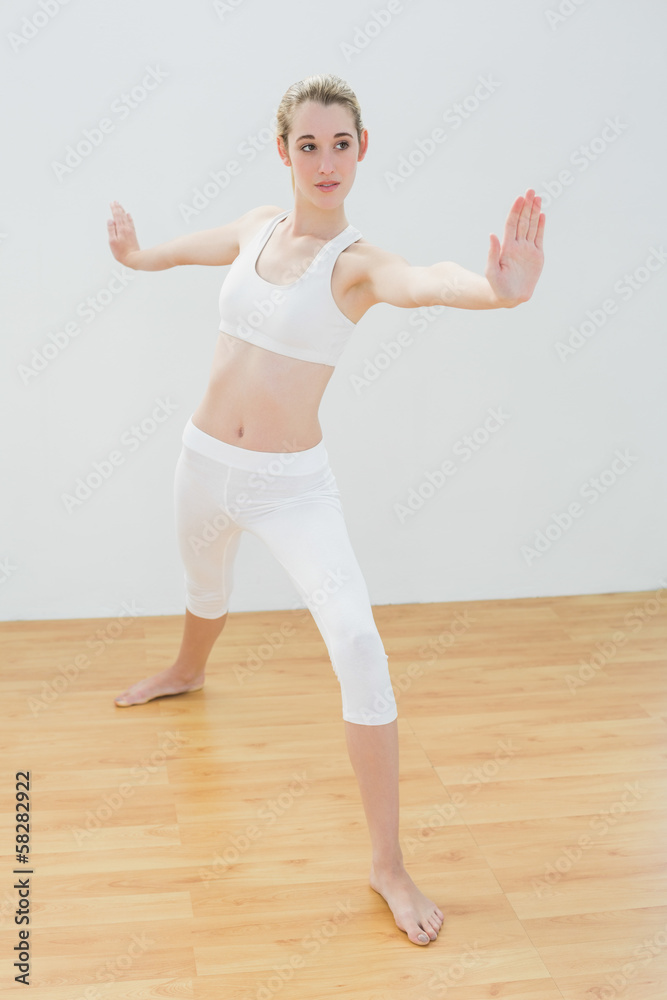 Focused fit woman practising yoga standing in sports hall Focused fit woman practising yoga standing in sports hall