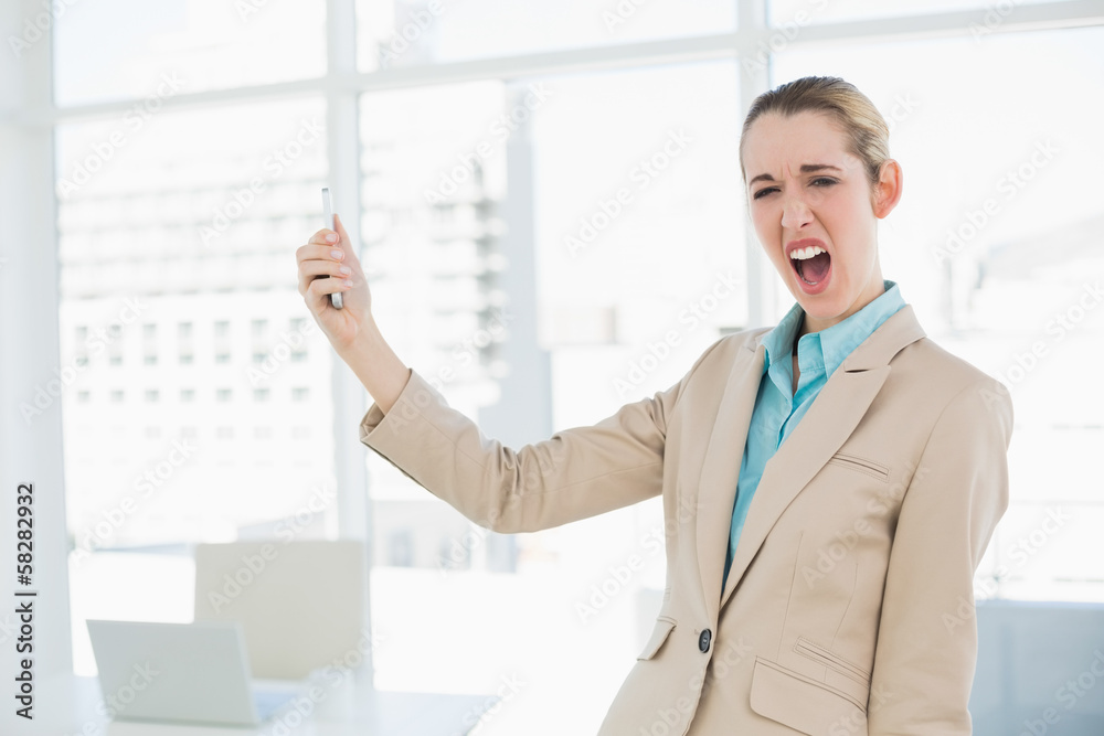 Cute shocked businesswoman holding her smartphone looking at cam Cute shocked businesswoman holding her smartphone looking at cam