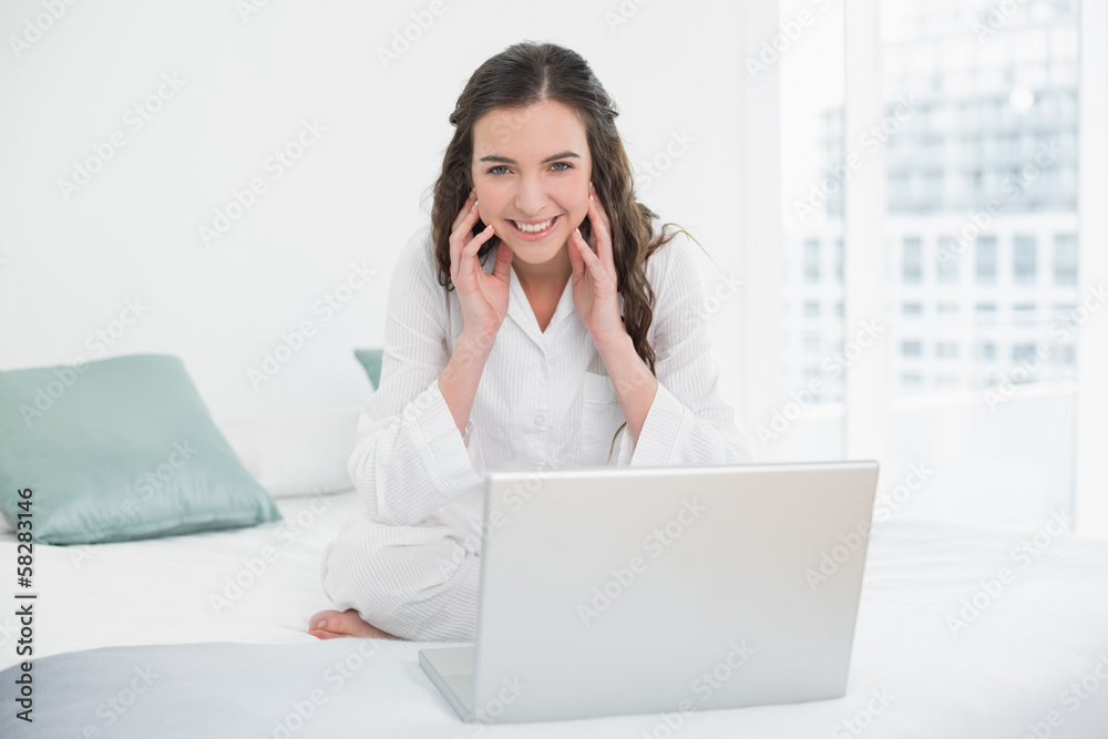Smiling casual brunette with laptop in bed Smiling casual brunette with laptop in bed