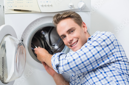 Smiling technician repairing a washing machine