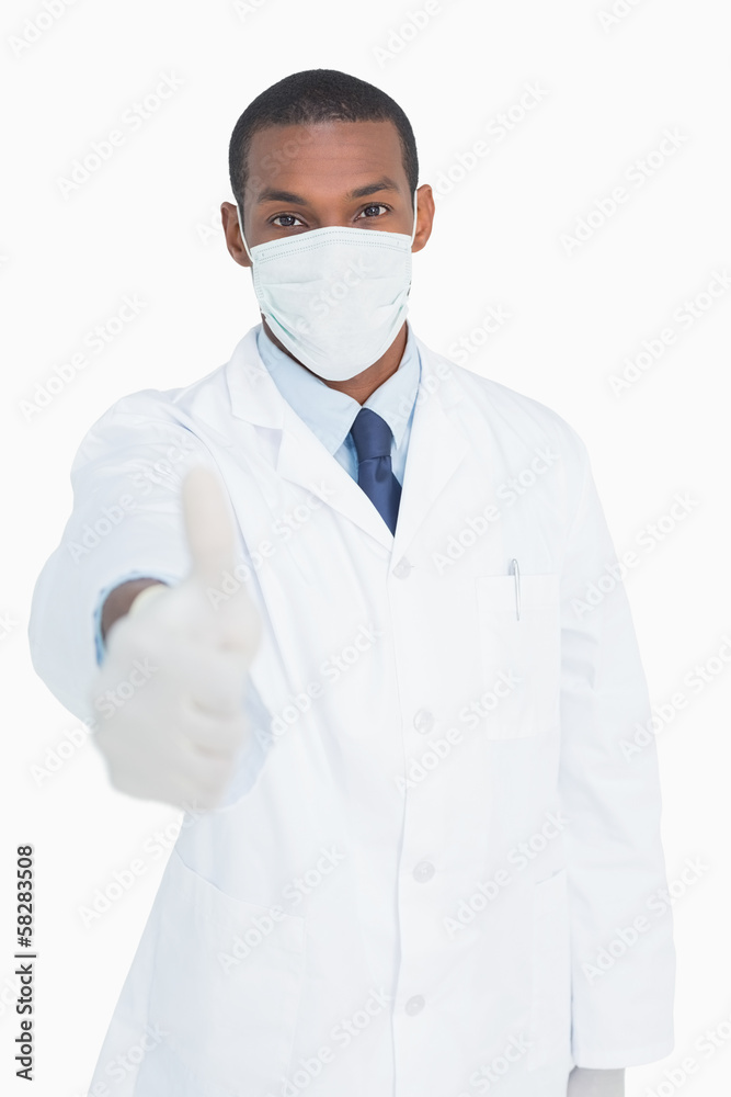 Portrait of male doctor in mask gesturing thumbs up