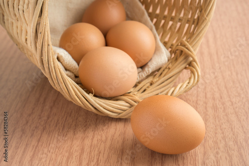 An egg on wooden table and eggs in a wicker basket