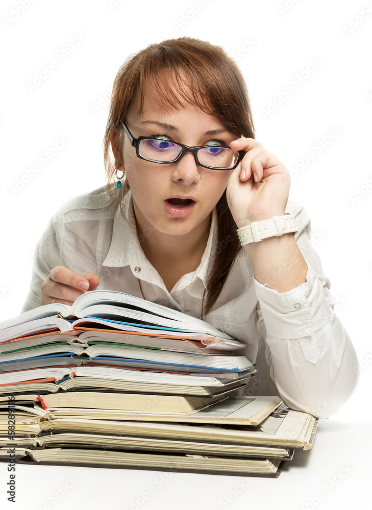 The girl sits at books and is surprised looks The girl sits at books and is surprised looks