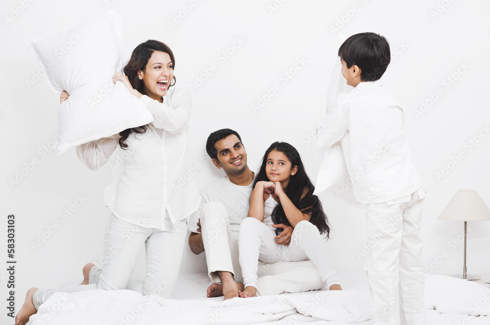 Happy family pillow fight on the bed