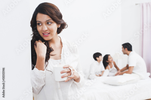 Woman enjoying a cup of coffee with her family in the background