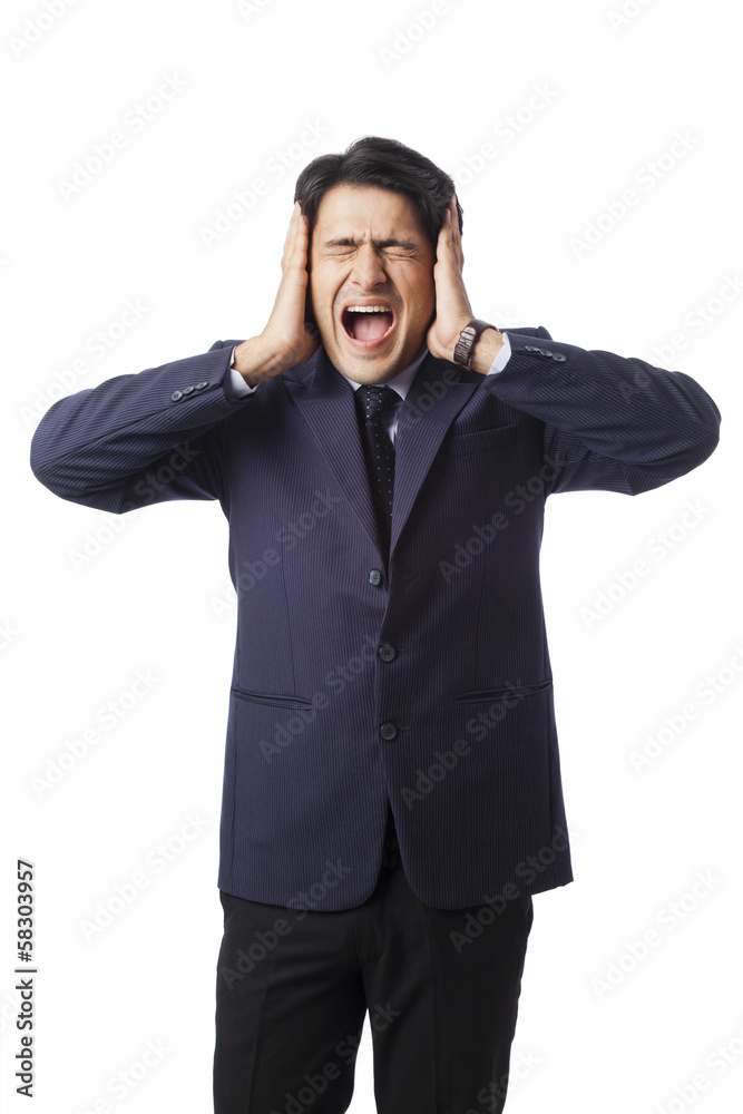 Businessman screaming with hands over his ears Businessman screaming with hands over his ears