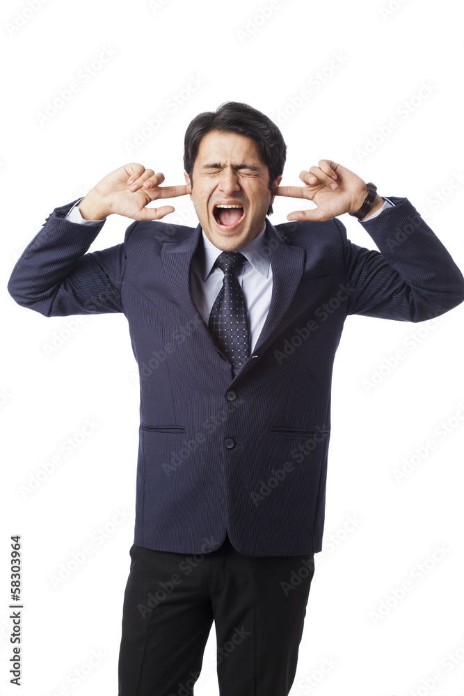 Businessman screaming with fingers in ears Businessman screaming with fingers in ears