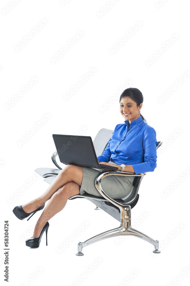 Businesswoman sitting on a bench and using a laptop Businesswoman sitting on a bench and using a laptop