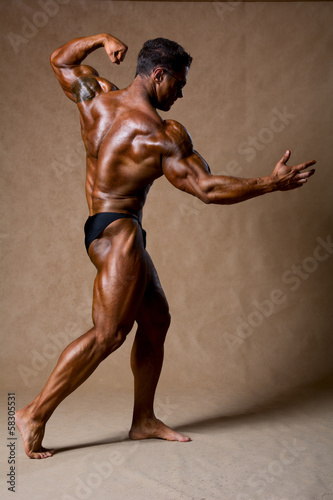 Bodybuilder flexing his muscles in studio.