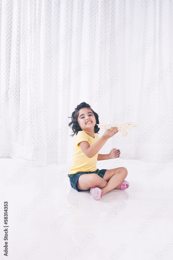 Girl playing with toy airplane and smiling