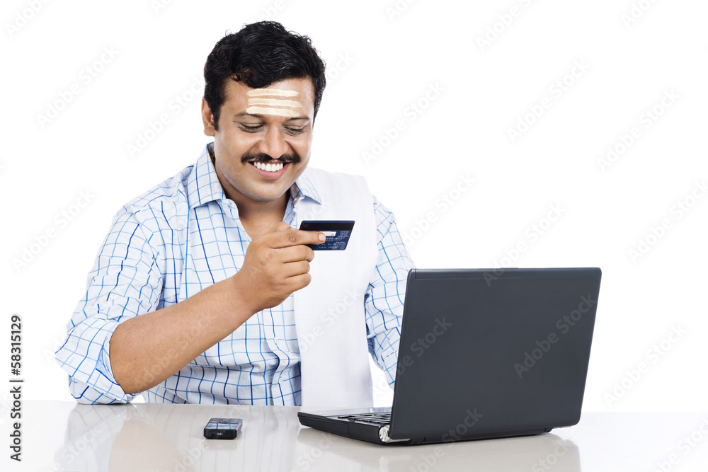 South Indian man doing online shopping with a credit card South Indian man doing online shopping with a credit card