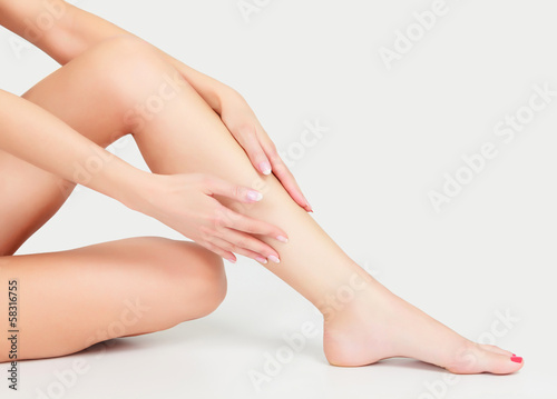 Fototapeta Woman sits on the floor and touches leg by hands