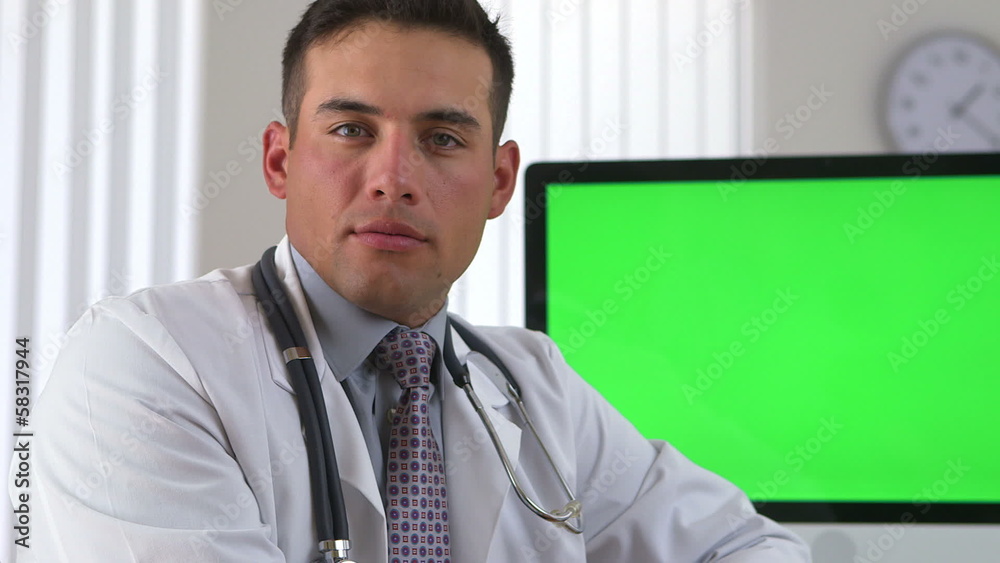 Hispanic doctor smiling with green screen on computer in backgro