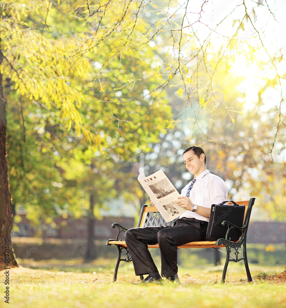 Young man on bench working on a laptop in a park Young man on bench working on a laptop in a park