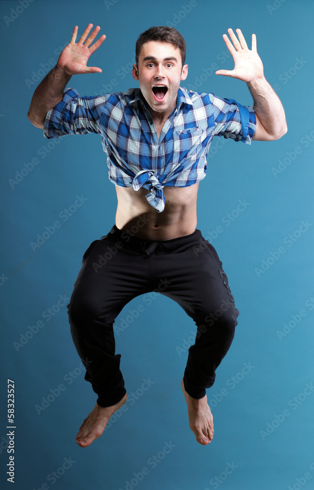Young man jumping isolated blue background