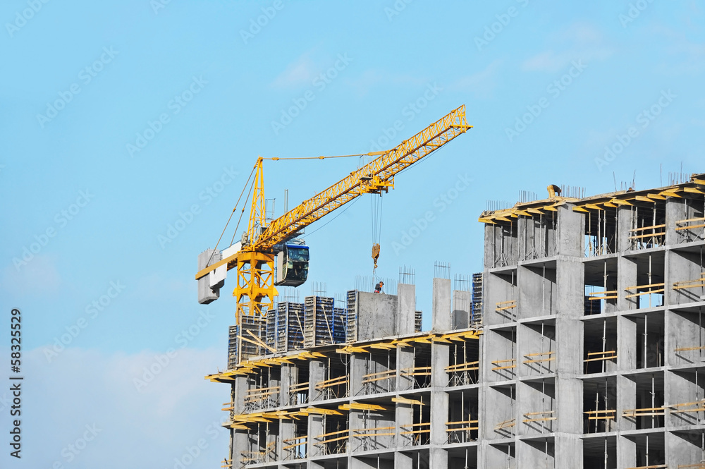 Crane and building construction site against blue sky