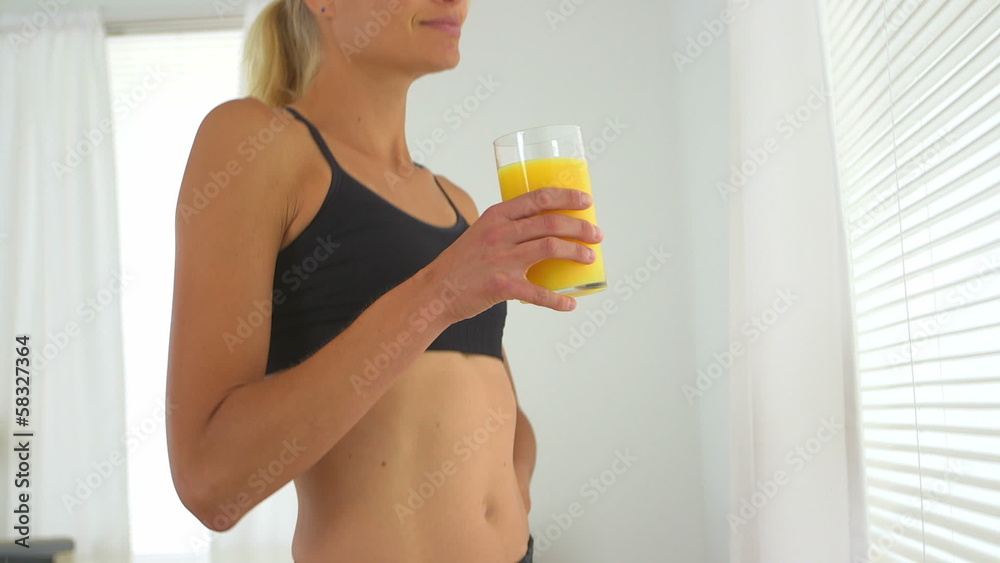 Healthy woman drinking orange juice wearing active wear Healthy woman drinking orange juice wearing active wear