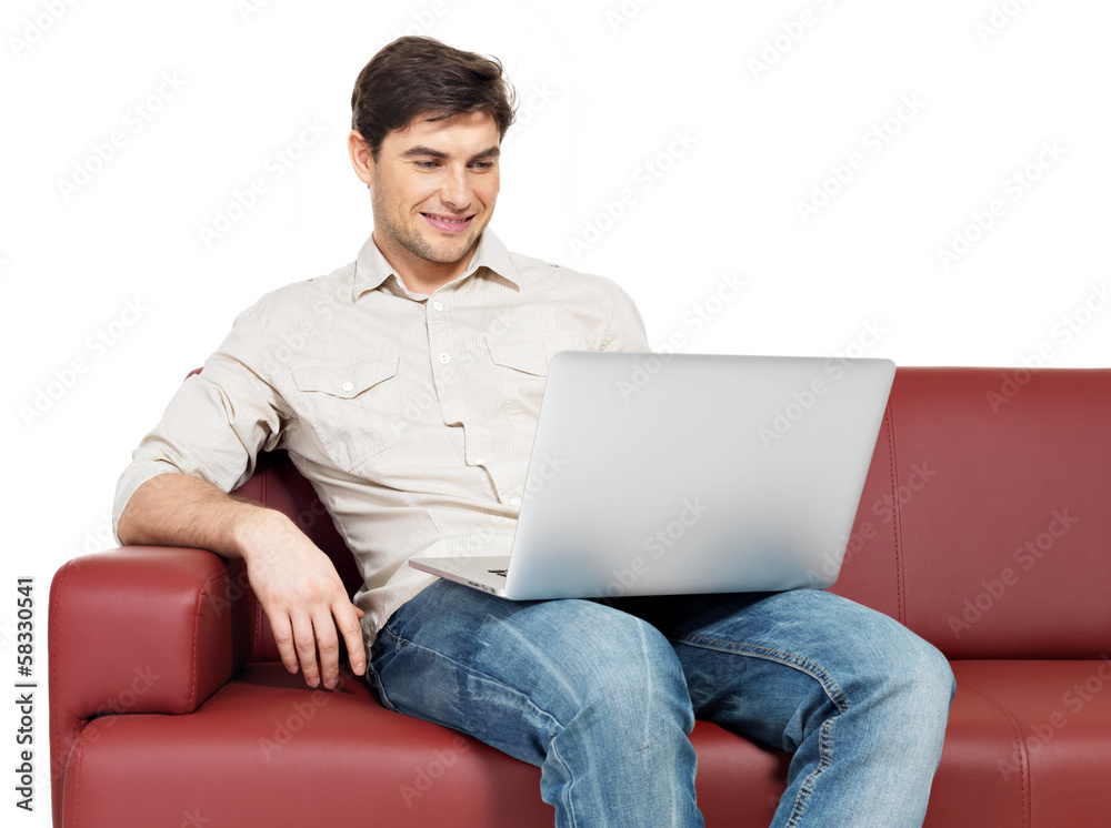 smiling happy man with laptop sits on the divan smiling happy man with laptop sits on the divan