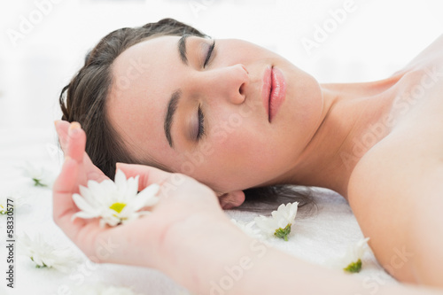 Beautiful woman with eyes closed and flowers in beauty salon