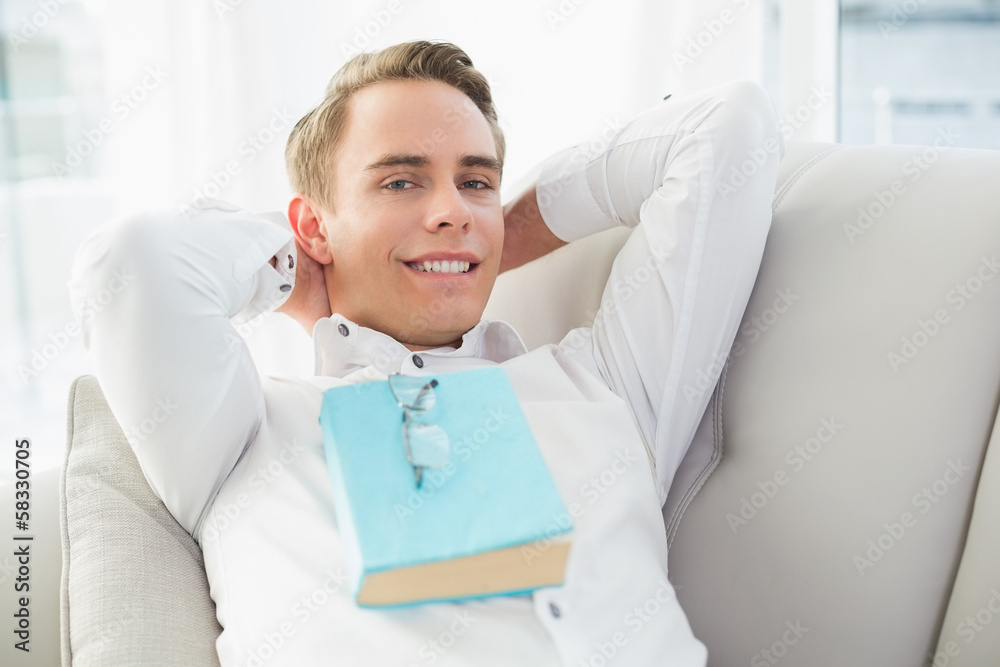 Portrait of a relaxed young man with book lying on sofa Portrait of a relaxed young man with book lying on sofa
