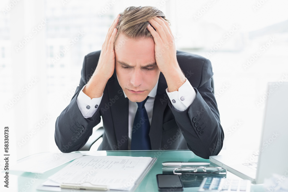 Worried businessman with head in hands at office desk Worried businessman with head in hands at office desk
