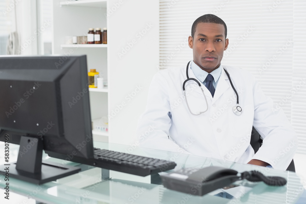 Serious male doctor with computer at medical office Serious male doctor with computer at medical office