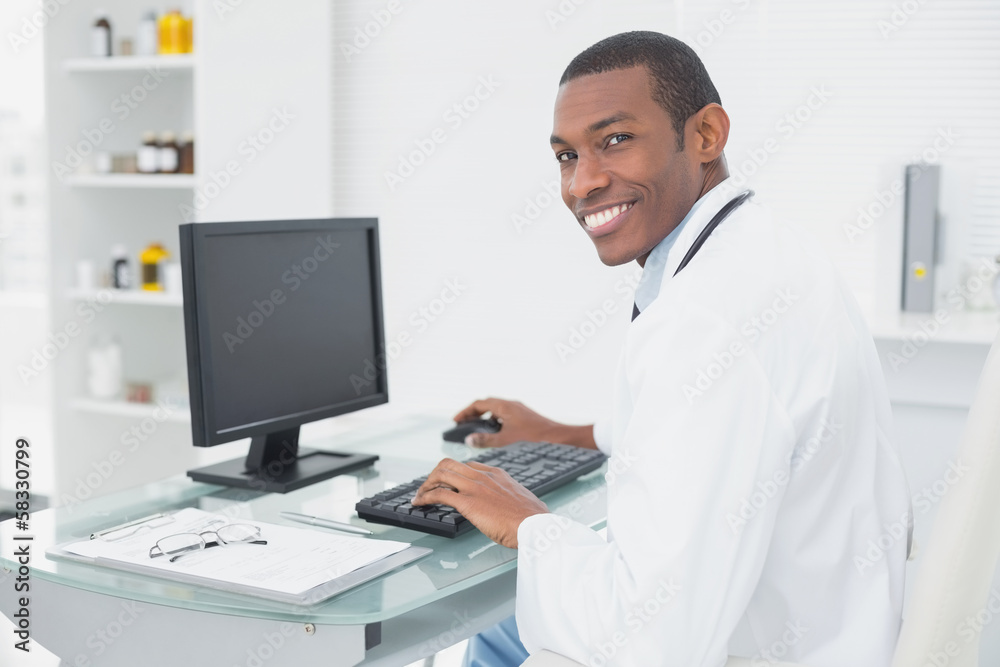 Smiling doctor using computer at medical office Smiling doctor using computer at medical office
