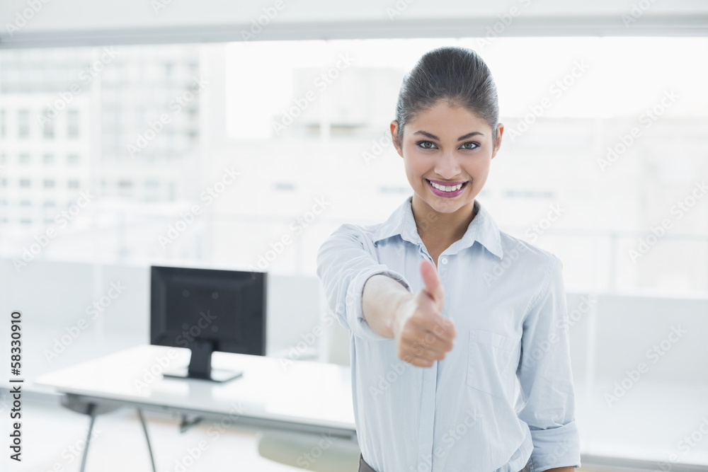 Smiling businesswoman gesturing thumbs up at office Smiling businesswoman gesturing thumbs up at office