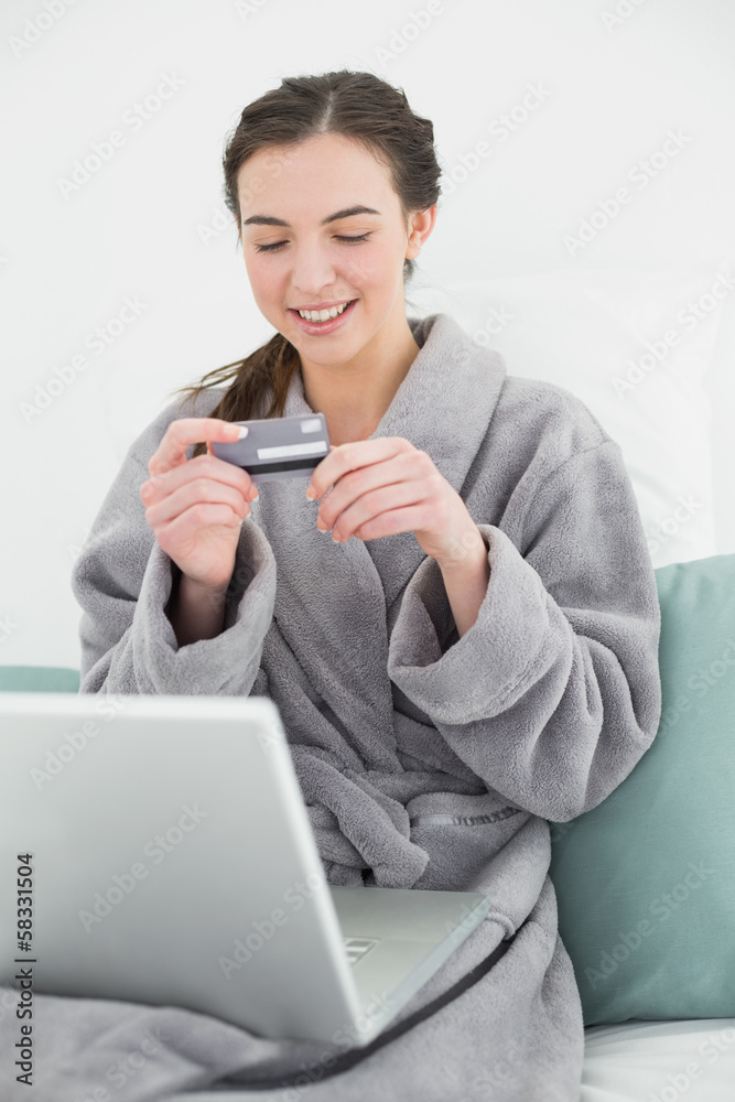 Casual woman in bathrobe doing online shopping in bed Casual woman in bathrobe doing online shopping in bed