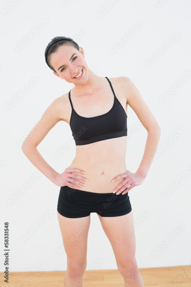 Smiling toned woman with hands on hips in fitness studio Smiling toned woman with hands on hips in fitness studio