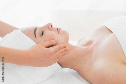 Hands massaging woman's face at beauty spa