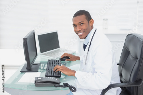 Wallpaper Mural Smiling doctor using computer at medical office Torontodigital.ca