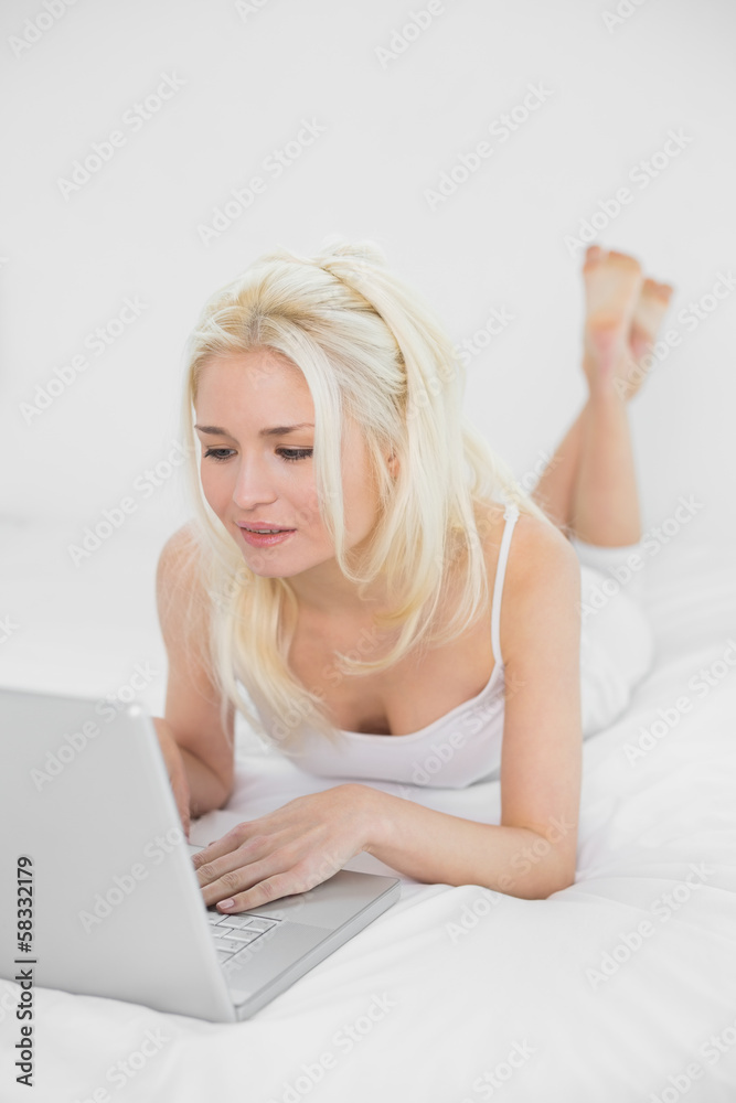 Casual relaxed young blond using laptop in bed Casual relaxed young blond using laptop in bed