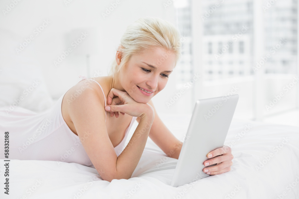 Content casual young blond using tablet PC in bed Content casual young blond using tablet PC in bed