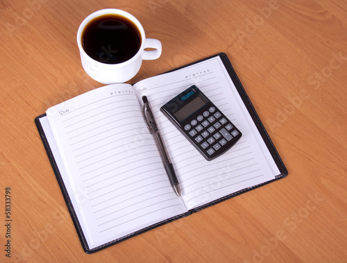 Open notepad, calculator and cup of coffee