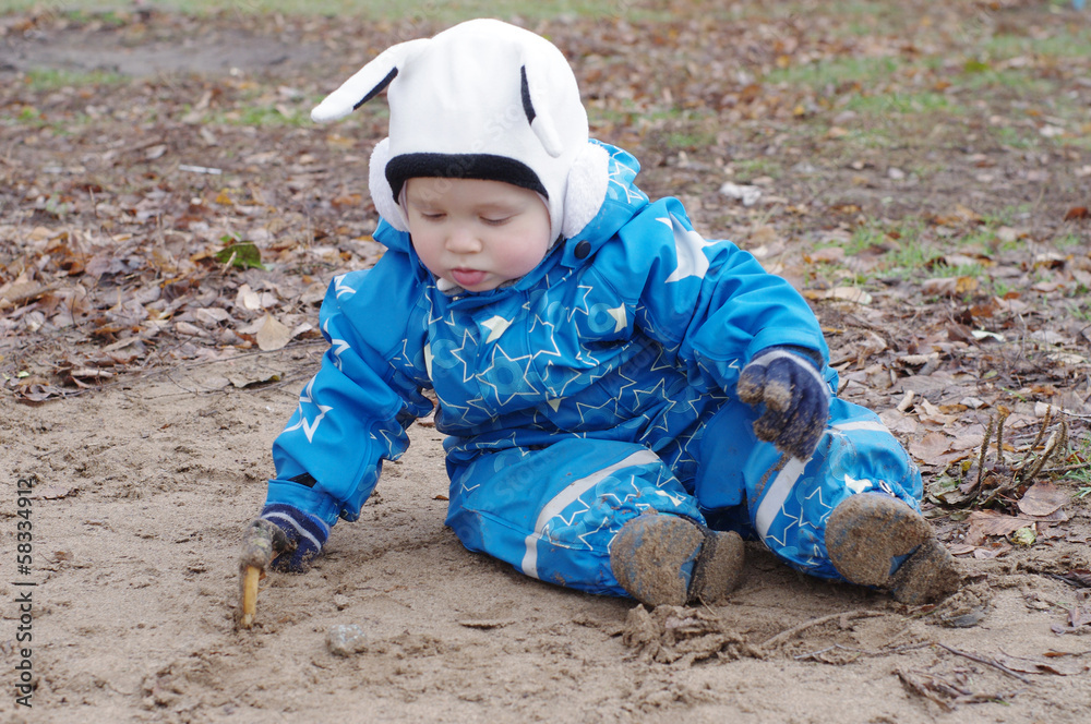 baby paints with stick sitting on ground baby paints with stick sitting on ground