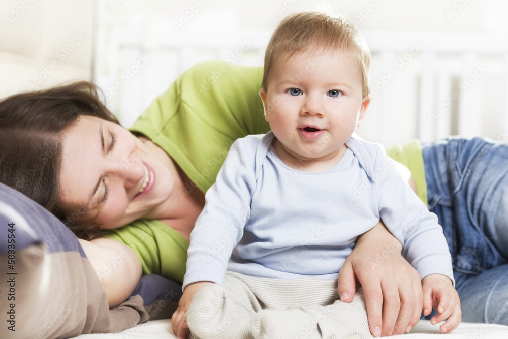 Happy family: Joyous mother and baby boy sitting in bed. Happy family: Joyous mother and baby boy sitting in bed.