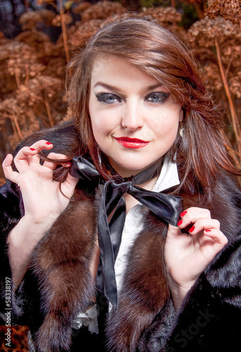 sexy woman smiling snidely and tying ribbon bow on neck photo