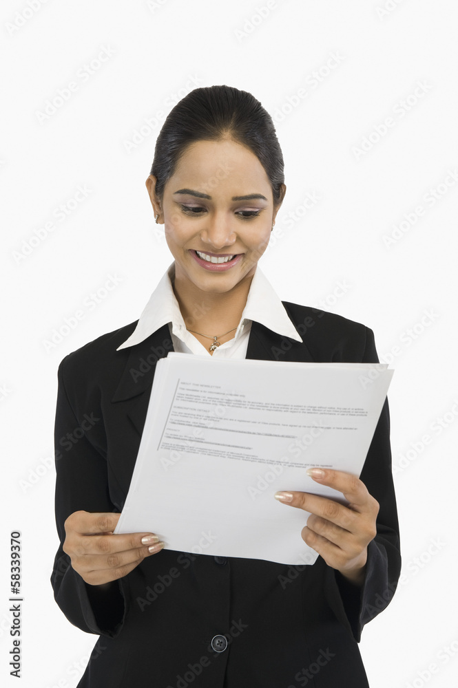 Businesswoman reading a document and smiling Businesswoman reading a document and smiling