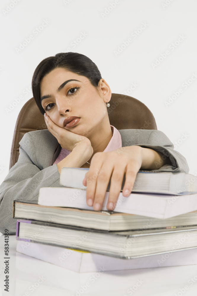 Businesswoman with a stack of books on a desk Businesswoman with a stack of books on a desk