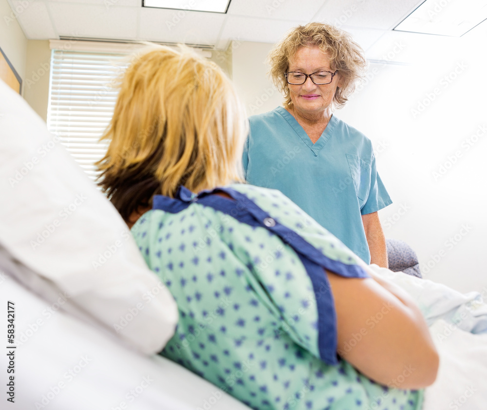 Obraz premium Nurse Looking At Newborn Babygirl With Mother In Hospital