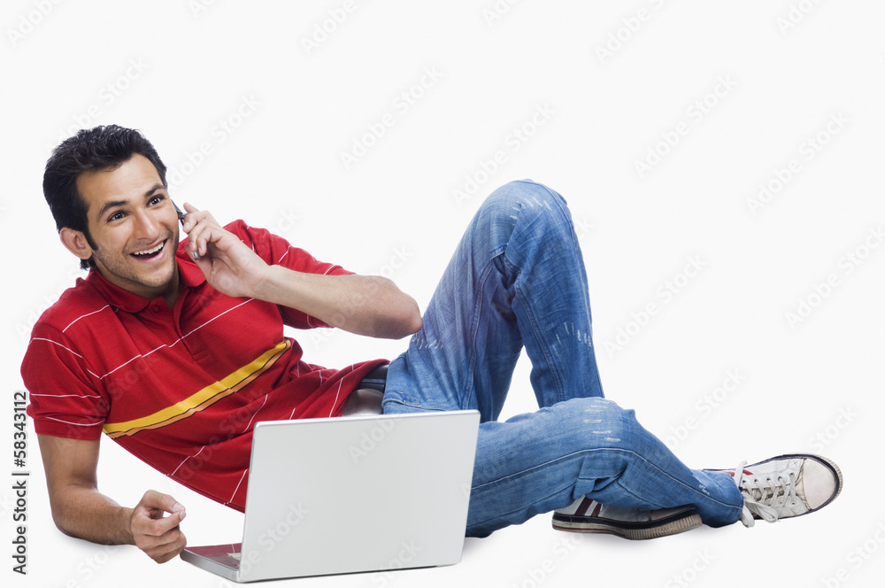 Man talking on a mobile phone while using a laptop