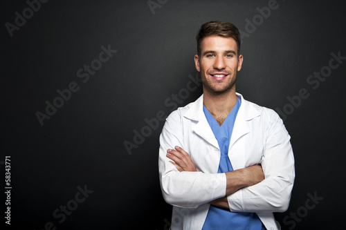Portrait of confident young medical doctor on dark background