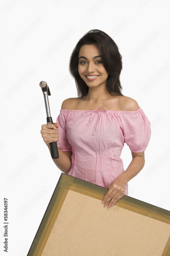 Portrait of a woman holding a hammer and a picture Portrait of a woman holding a hammer and a picture